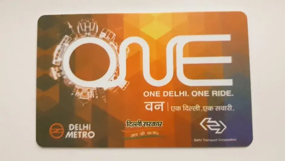 Someone using a Delhi Metro smart card at the station gate for the first time, learning how to tap and travel easily.